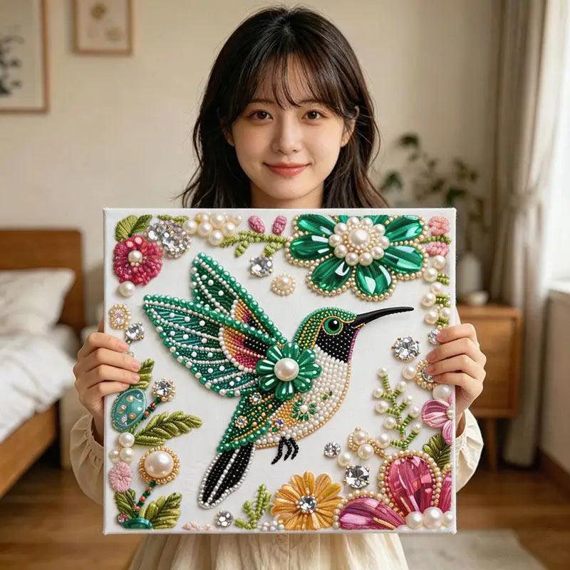 A woman holds a finished diamond painting of a vibrant green and black bird adorned with pearls and diamonds.