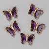 A set of crystal butterfly charm beads in purple and gold for jewelry making.