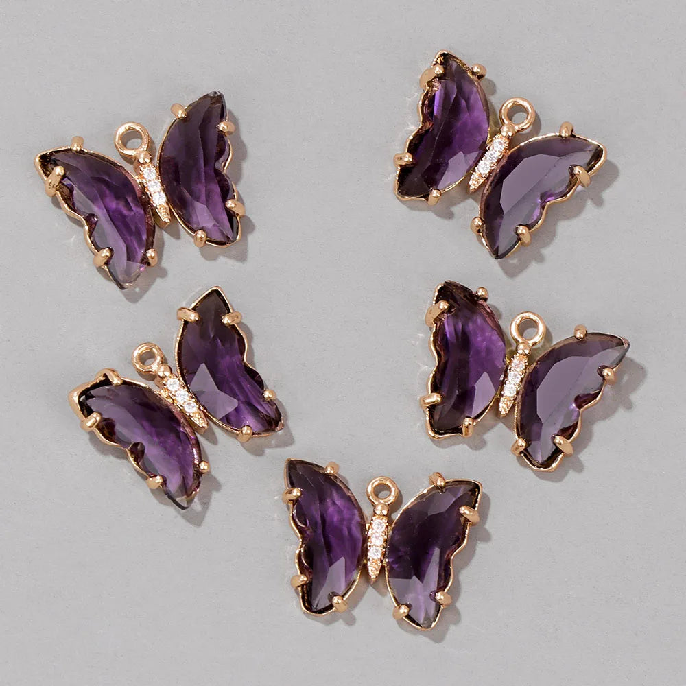 A set of crystal butterfly charm beads in purple and gold for jewelry making.