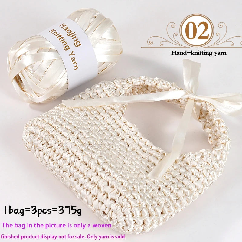 A hand-knitted cream woven bag made from white yarn next to a ball of beige knitting yarn.