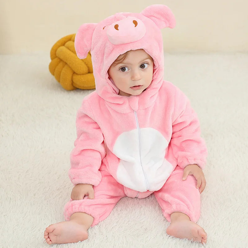A baby wearing a pink hooded romper shaped like a pig, sitting on a white surface.