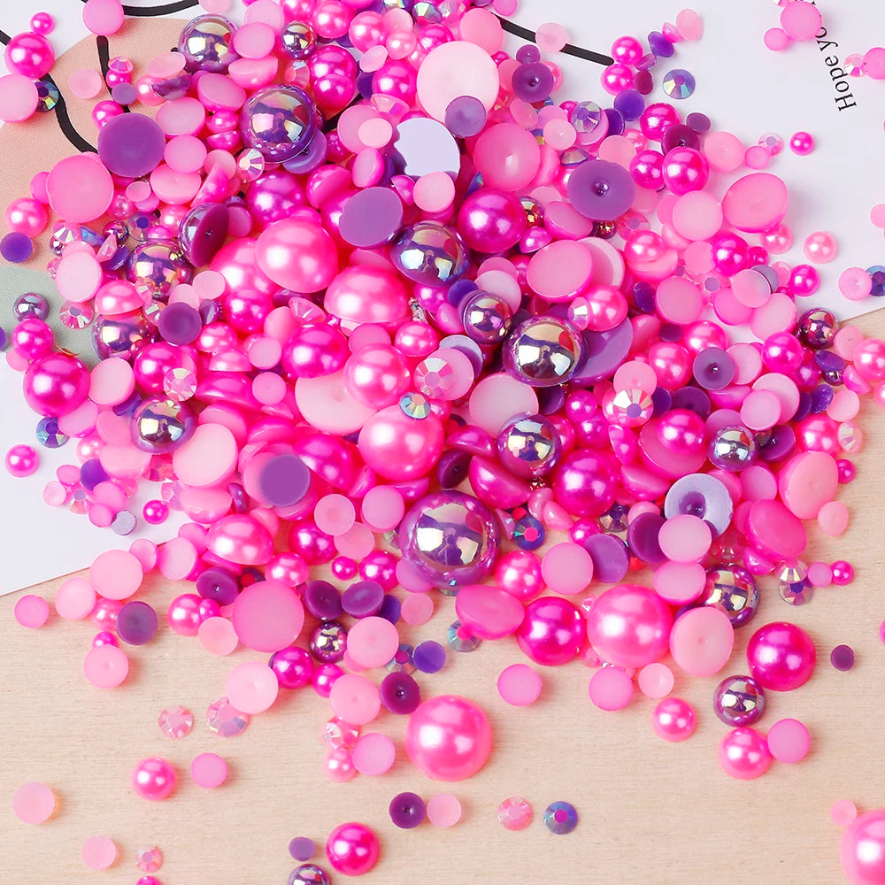 A pile of mixed resin rhinestone pearls in various shades of pink and purple scattered on a light surface.