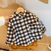 A plaid button-up shirt with black and white checks is displayed on a hanger against a light background.
