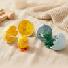 A collection of colorful wind-up bouncing chick toys, including yellow and orange chicks, resting on a beige fabric.