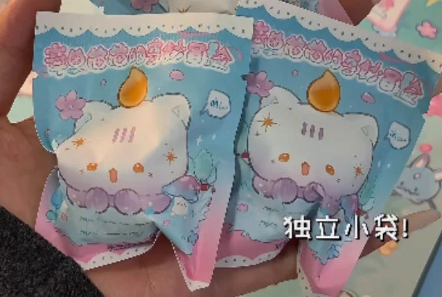 A hand holds a package of cute mini bean blind box figurines featuring strawberry mousse tower and octopus cat pendant charms
