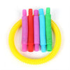 A set of colorful telescopic pop tubes in pink, red, blue, and green arranged around a yellow coiled ring.