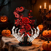 A gothic skeleton hand and rose cross building set displayed on a rustic table with pumpkins.