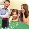 A family is gathered around a green table with a leather dice cup and five dice for gaming.