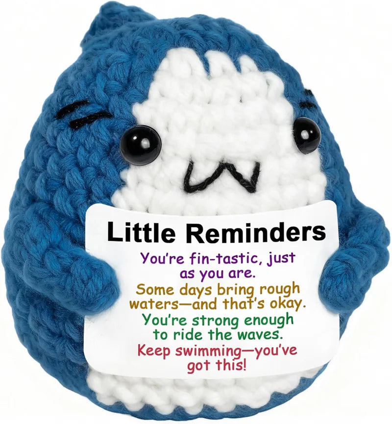 A blue and white crochet plush toy with a smiling face and a message encouraging resilience to ride the waves.
