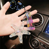 A hand holds a clear starfish charm attached to a colorful, iridescent pendant keychain.