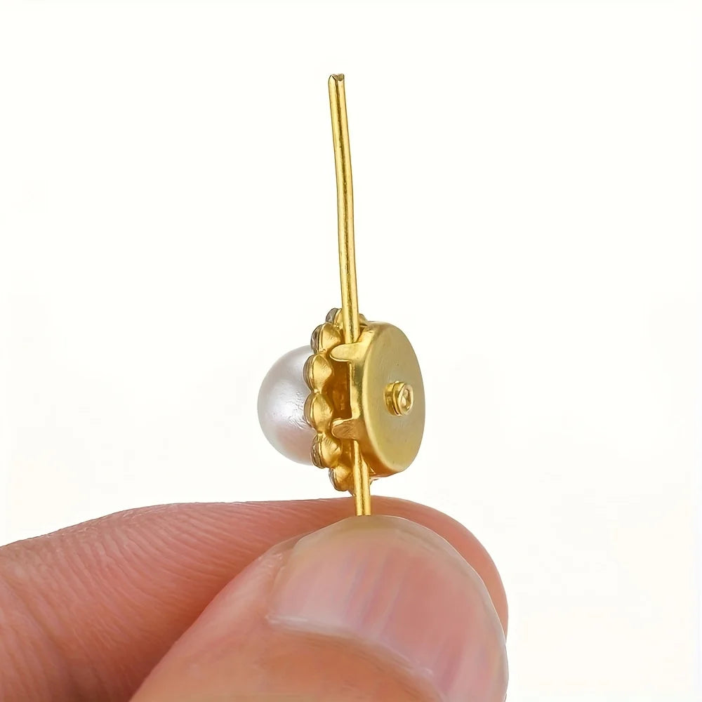 A gold-toned jewelry finding featuring a pearl bead and a gold wire hook.