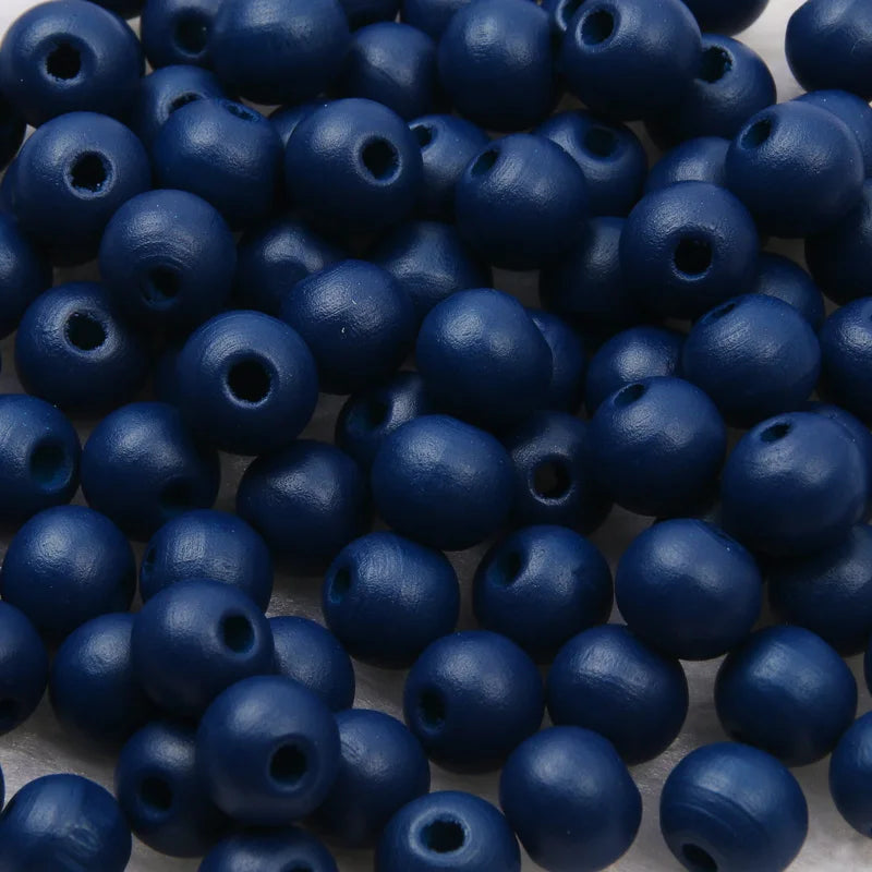 A pile of small, dark blue wooden beads for jewelry making and DIY crafts.