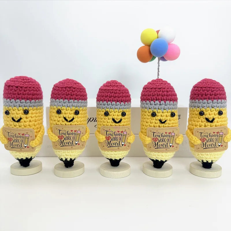 Five handwoven crochet pencil ornaments in shades of pink and yellow with a multicolored balloon string.