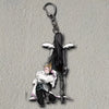 Acrylic figure stand of a character in a white coat and dark clothing with a hanging metal charm.