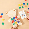 A wooden Montessori lacing board toy for children with colorful pieces and ropes is being held over a scattered assortment of