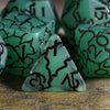 A close-up of a green frosted crack resin polyhedral dice set with black markings, including a triangular die.