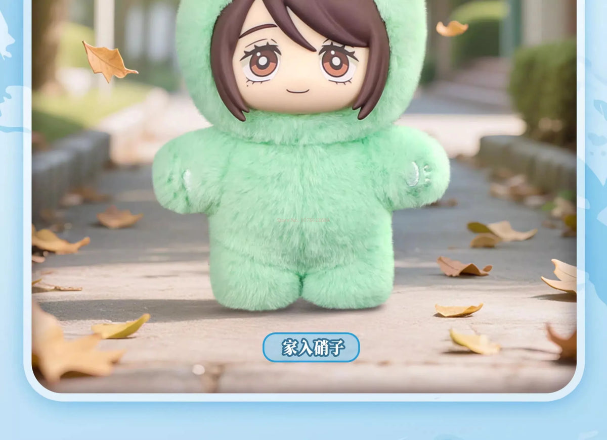 A plush blind box pendant of a green, fuzzy cat character with brown hair standing on a wooden surface.