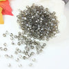 A pile of faceted gray and clear crystal beads is displayed on a white surface.