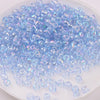 A pile of iridescent light blue glass rice beads for DIY jewelry and crafting.