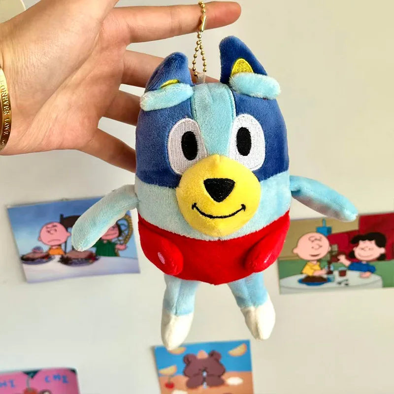 A hand holds a blue plush doll resembling a dog character, likely Bluey, against a white background.