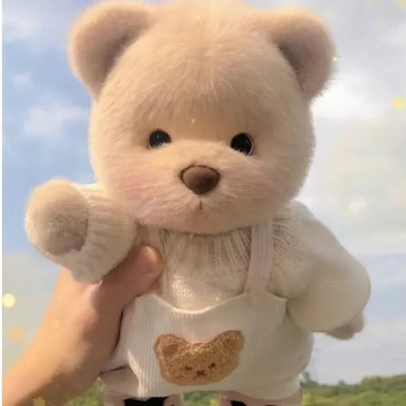 A hand is holding a white teddy bear plush with a knitted dress against a bright sky background.