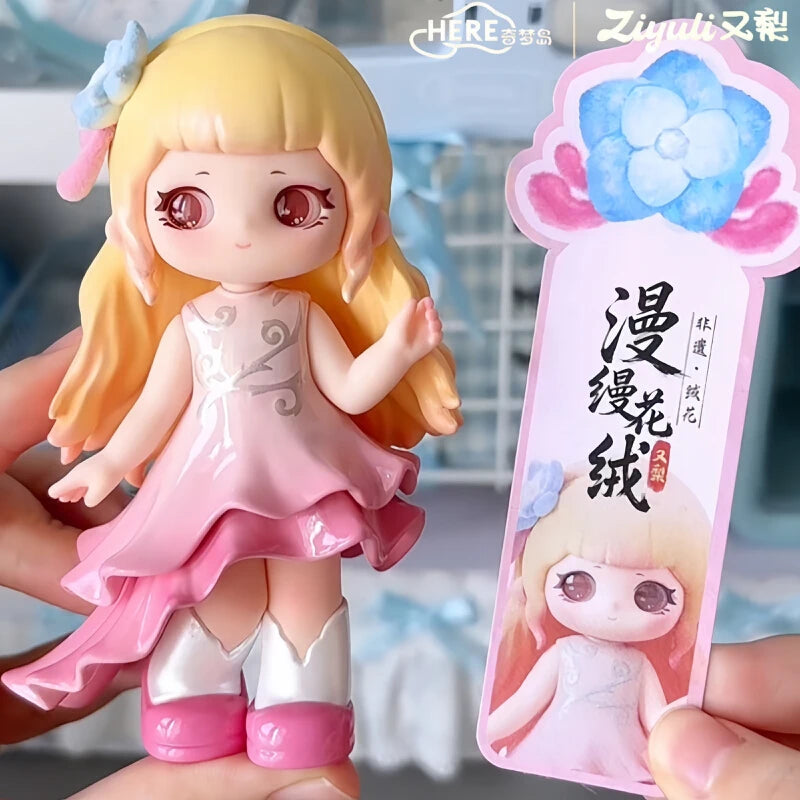 A figurine of a girl with long blonde hair and pink clothing is held in a hand, displayed next to its packaging.