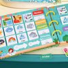 A colorful Montessori busy book featuring themed cards for days of the week and weather, displayed on a light wooden surface.