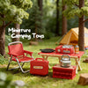 A miniature camping set featuring a red folding chair, gas stove, and oven box displayed in a forest setting.
