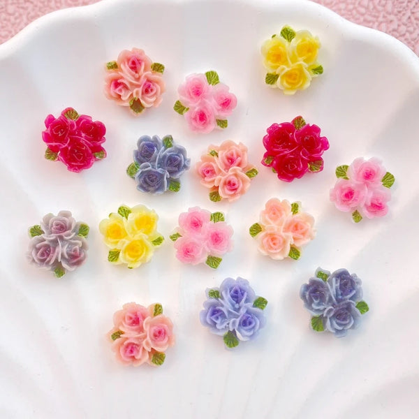 A collection of nine resin flower ornaments in pink, yellow, and purple hues arranged on a white plate.