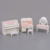 A set of 1:12 scale dollhouse furniture including a piano, vanity with a mirror, and a chair in pink and white.