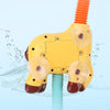 A yellow giraffe spray water toy with orange and teal squeeze tubes is shown against a light blue background.