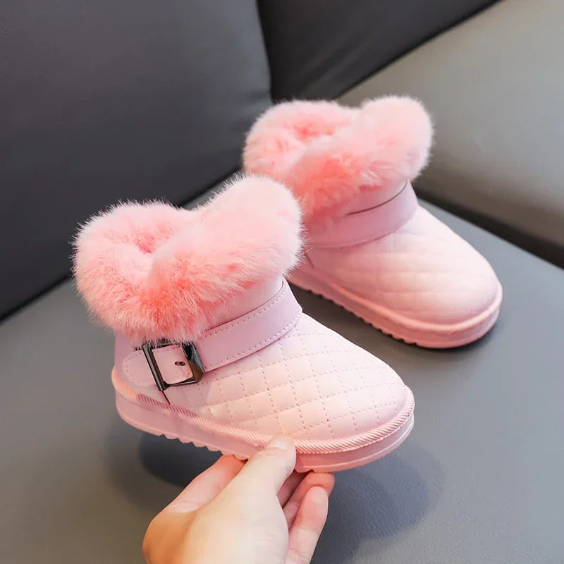 Pink girls snow boots with fluffy pink lining and a silver buckle being held by a hand.