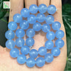 A hand holds a string of natural light blue chalcedony beads for jewelry making