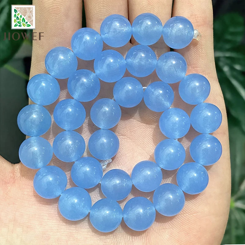 A hand holds a string of natural light blue chalcedony beads for jewelry making