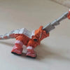 A die-cast dinosaur truck toy with a removable dino figure in orange and gray.
