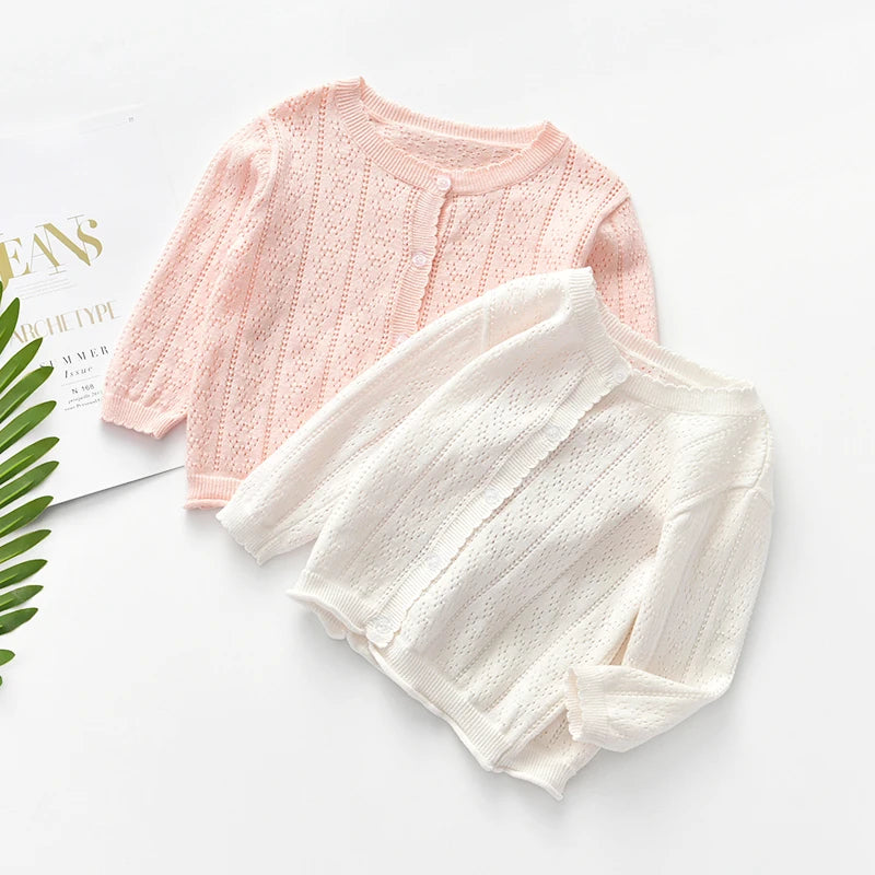 A light pink knitted cotton cardigan sweater laid flat on a white surface.