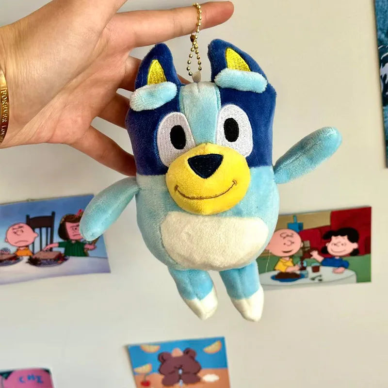 A fluffy blue and white plush toy of a dog, resembling Bingo from Bluey, being held by a hand.