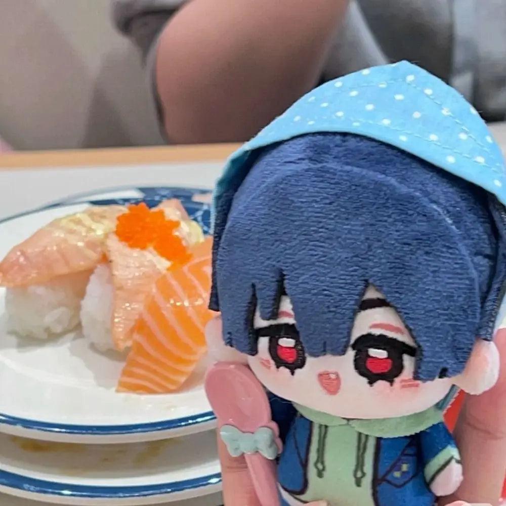 A plush doll of an anime character with blue hair and a light blue polka-dot cap, holding a piece of orange fish sushi.