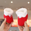 A pair of red baby first walker shoes with fluffy white trim being held by a person.