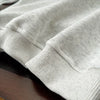 A light gray kids' 2-piece long-sleeve sweater and sweatpants set folded on a wooden surface.