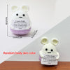A white crocheted bunny doll with an inspirational quote tag on a light purple background.