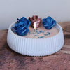 A white silicone mold containing three fabric roses in shades of blue and dusty rose on a wooden surface.