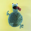A handmade crochet lizard with open mouth and red tongue sitting on a yellow background.