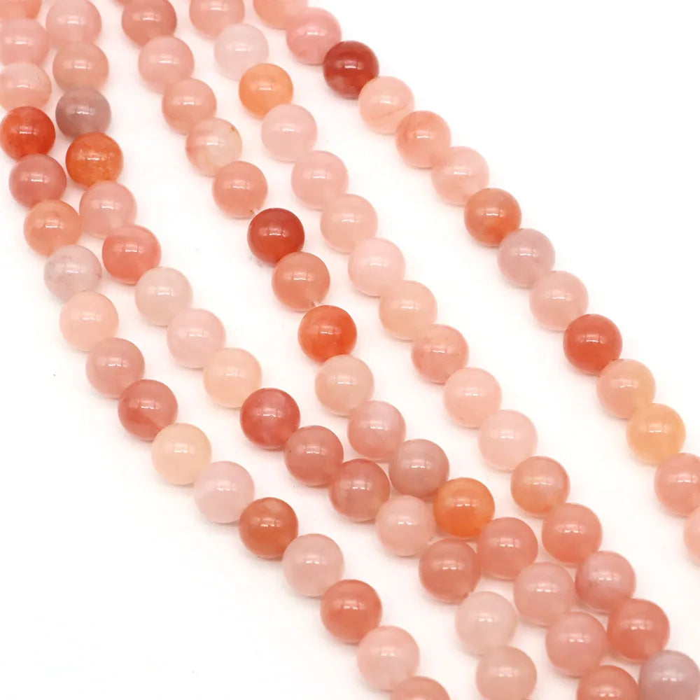 Strands of natural stone round beads in shades of pink, orange, and red for jewelry making