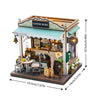 A wooden miniature coffee shop house kit featuring a storefront, interior display, and wooden furniture.