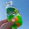 A hand holds a clear bottle filled with green liquid and floating fruit toys, labeled Chiboki.