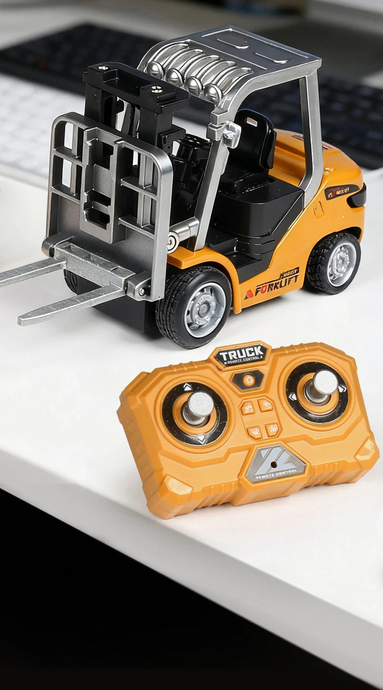 A yellow and black mini RC forklift truck model with a metal fork and an orange remote control transmitter.