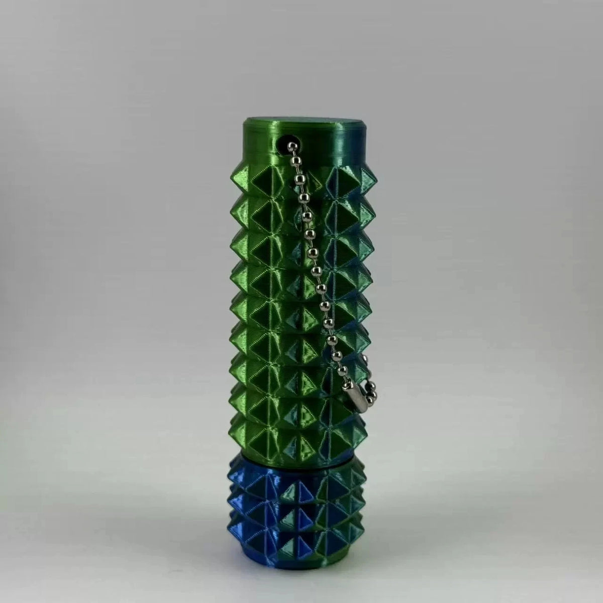 A green 3D printed spike roller fidget toy with a silver keychain, shown vertically.