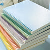 A stack of colorful macaron detachable spiral notebooks with light green, pink, and yellow covers.