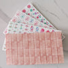 A set of pearl pink acrylic American Mahjong tiles stacked diagonally on a marble surface.